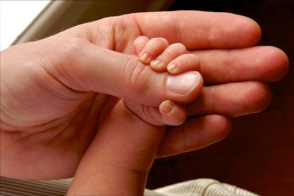 Fotografía de una mano de bebé cogiendo una mano adulta. © Killroy Productions